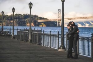 man and woman kissing beside metal rail guard